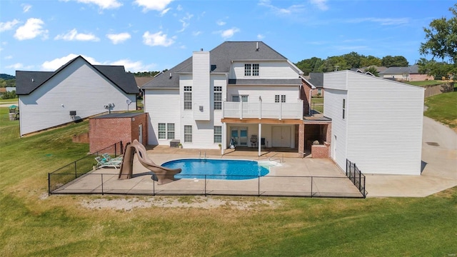 back of property with a balcony, a patio, and a lawn