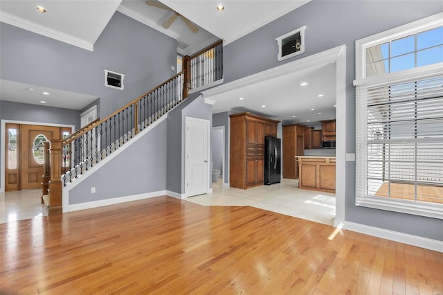 unfurnished living room featuring light hardwood / wood-style flooring, ornamental molding, a healthy amount of sunlight, and a high ceiling