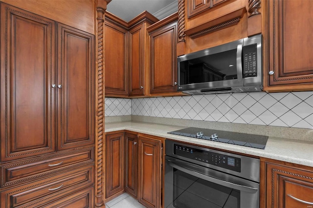 kitchen with light stone counters, appliances with stainless steel finishes, built in desk, and backsplash