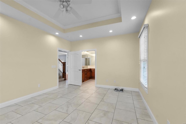 tiled spare room featuring a raised ceiling, crown molding, and ceiling fan