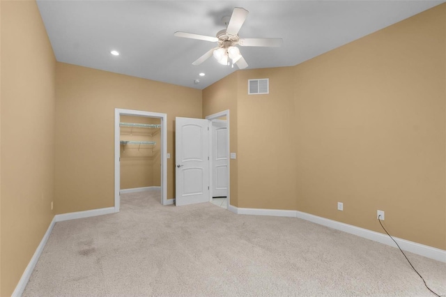 unfurnished bedroom featuring light carpet, a spacious closet, a closet, and ceiling fan