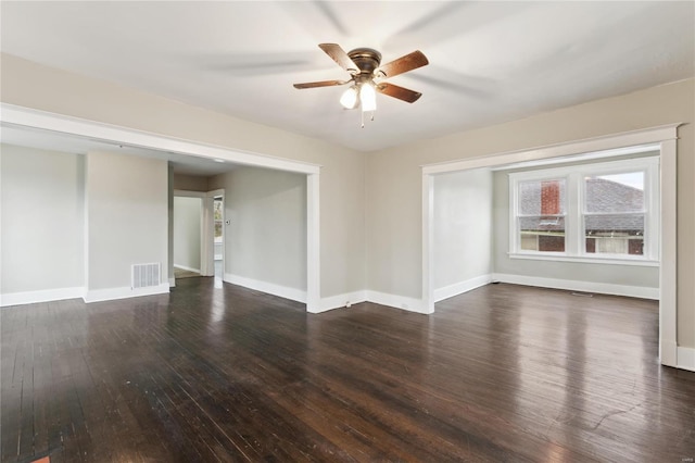 spare room with dark wood-style floors, visible vents, baseboards, and ceiling fan