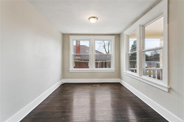 spare room featuring dark wood-style flooring and baseboards