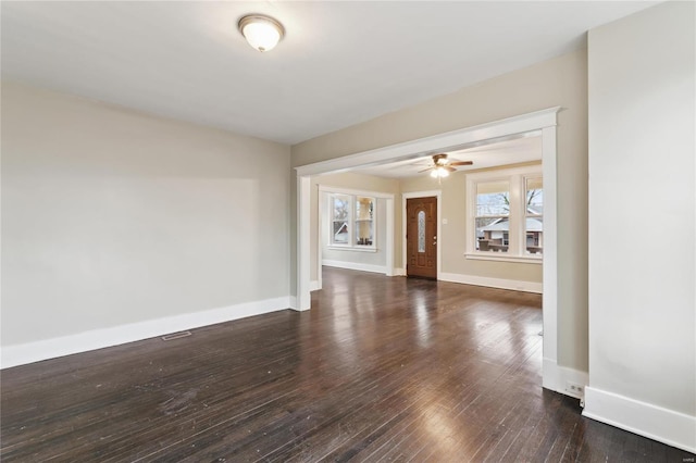 spare room featuring wood-type flooring, visible vents, ceiling fan, and baseboards