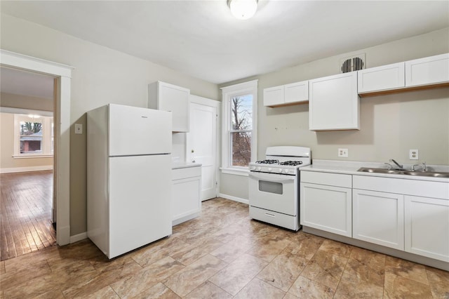 kitchen with white appliances, baseboards, light countertops, white cabinetry, and a sink