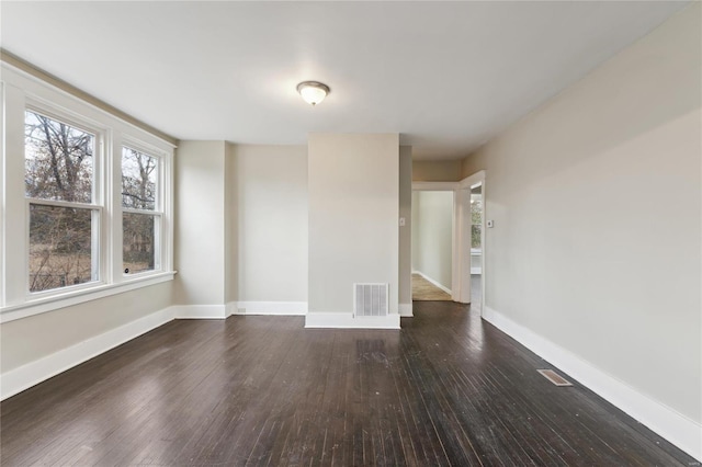 spare room with baseboards, visible vents, and dark wood finished floors