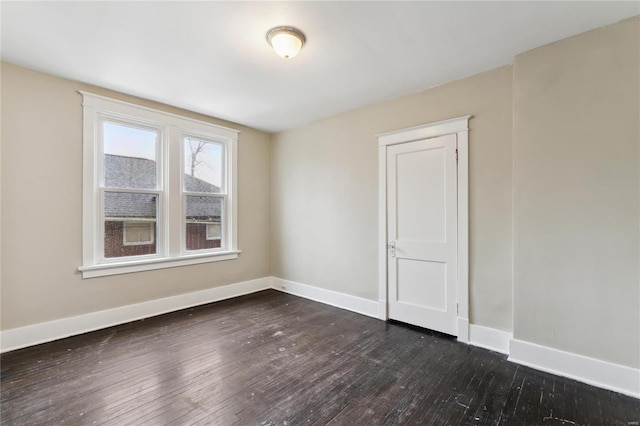 spare room featuring baseboards and hardwood / wood-style flooring