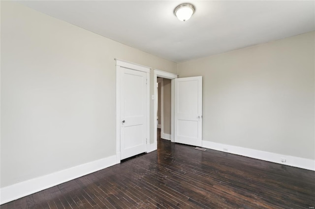 spare room featuring hardwood / wood-style flooring and baseboards