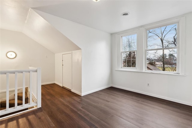 additional living space featuring lofted ceiling, dark wood-style flooring, visible vents, and baseboards