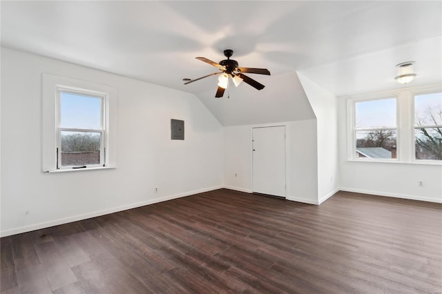 additional living space with electric panel, baseboards, ceiling fan, dark wood-type flooring, and vaulted ceiling