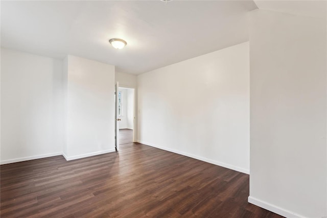 spare room featuring baseboards and dark wood finished floors