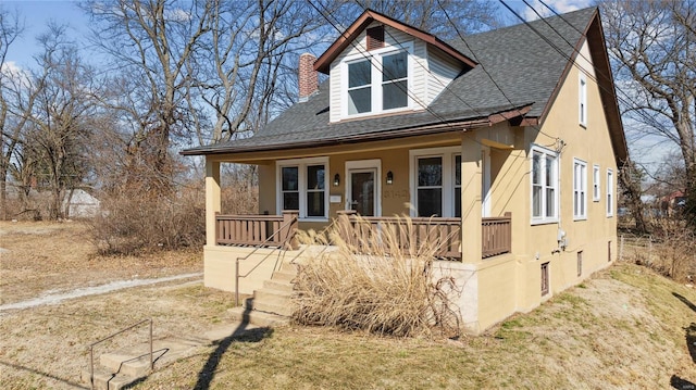 view of front of house featuring covered porch, a shingled roof, and a chimney