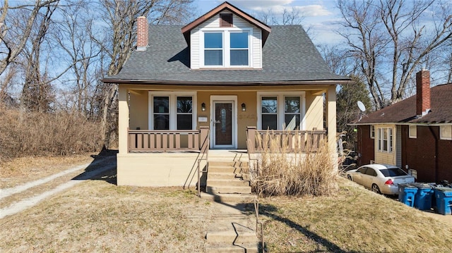 bungalow-style house featuring stucco siding, a chimney, a porch, and roof with shingles