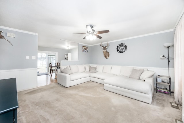 carpeted living room with ceiling fan and ornamental molding