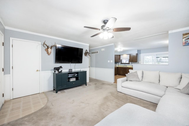 carpeted living room featuring crown molding and ceiling fan