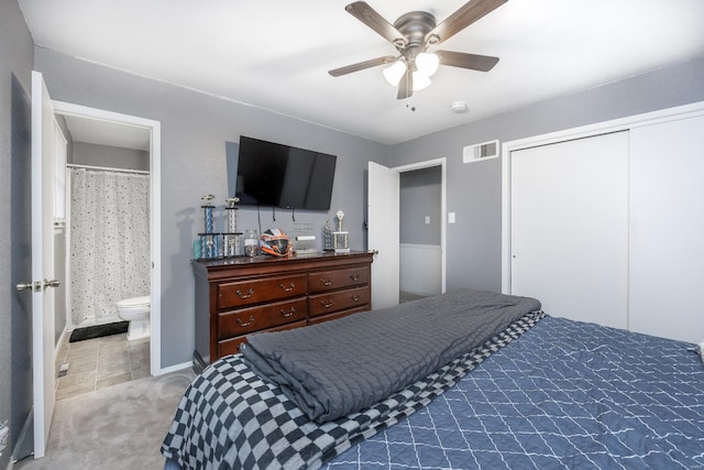 carpeted bedroom featuring ceiling fan, ensuite bath, and a closet