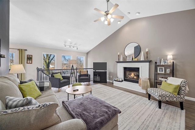 living room with wood-type flooring, a brick fireplace, lofted ceiling, and ceiling fan