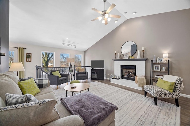 living room featuring vaulted ceiling, ceiling fan, hardwood / wood-style floors, and a brick fireplace