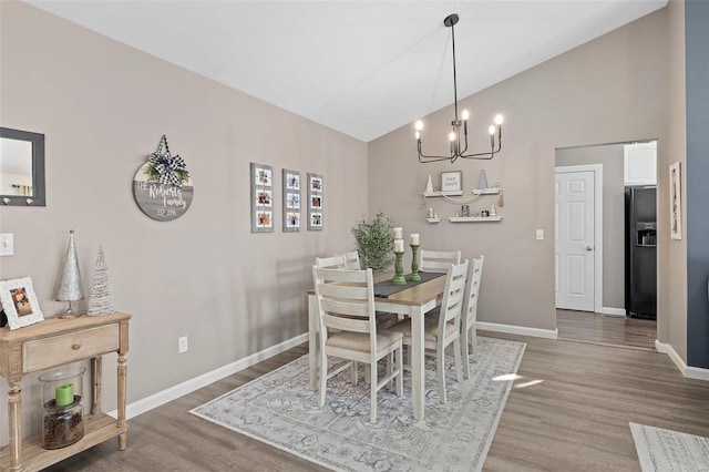 dining room with lofted ceiling, hardwood / wood-style floors, and an inviting chandelier