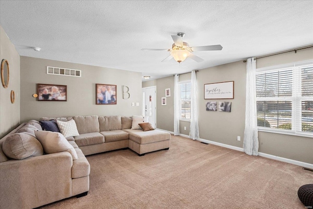 carpeted living room with ceiling fan and a textured ceiling