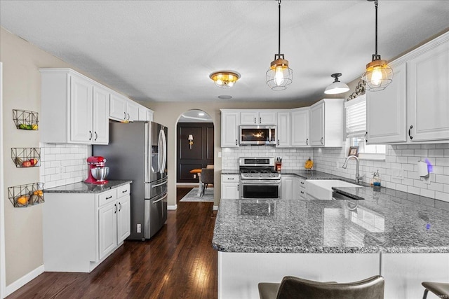 kitchen featuring white cabinetry, stainless steel appliances, kitchen peninsula, and hanging light fixtures