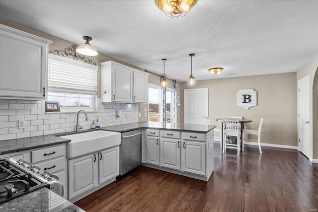 kitchen featuring sink, dishwasher, white cabinetry, decorative light fixtures, and kitchen peninsula