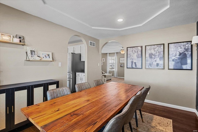 dining area featuring a tray ceiling and dark wood-type flooring