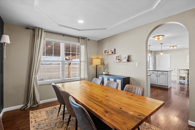 dining room featuring a raised ceiling, dark hardwood / wood-style flooring, and a textured ceiling