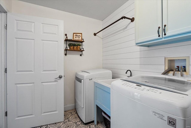 clothes washing area featuring cabinets, light tile patterned flooring, separate washer and dryer, and wooden walls