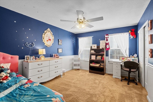 bedroom featuring ceiling fan, a closet, light carpet, and a textured ceiling