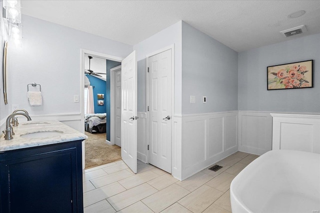 bathroom featuring vanity, a washtub, ceiling fan, tile patterned floors, and a textured ceiling