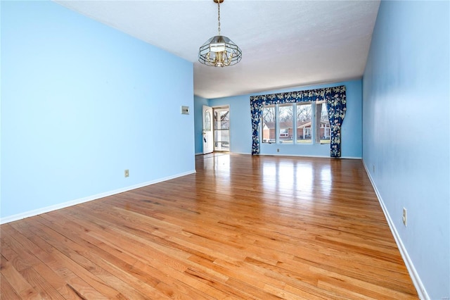 empty room featuring an inviting chandelier and light hardwood / wood-style floors