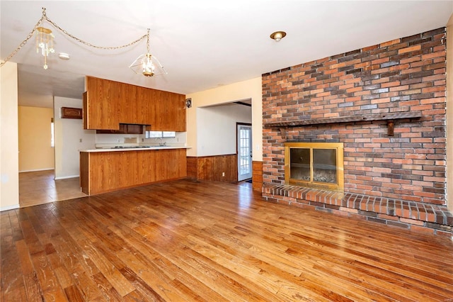 kitchen featuring light hardwood / wood-style floors, wood walls, a fireplace, and kitchen peninsula