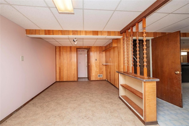 empty room with wooden walls and a paneled ceiling