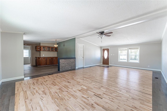 unfurnished living room featuring crown molding, vaulted ceiling, a textured ceiling, light wood-type flooring, and ceiling fan