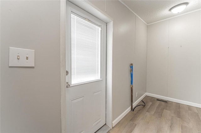 clothes washing area with ornamental molding, a textured ceiling, and light hardwood / wood-style floors