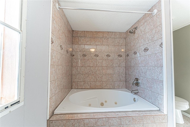 bathroom with tiled shower / bath combo, a textured ceiling, and toilet