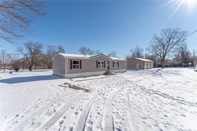 snow covered back of property featuring a garage