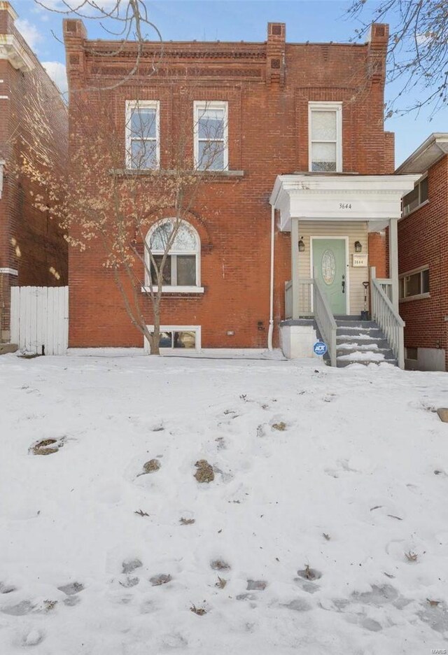 view of front of home with a garage, brick siding, and fence