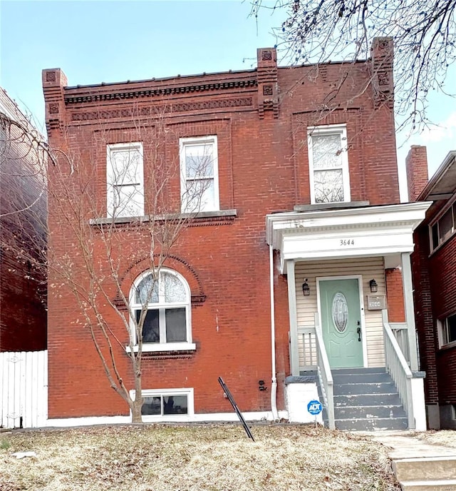 view of front facade with brick siding and fence