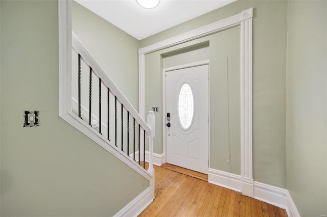 foyer entrance featuring hardwood / wood-style flooring, stairway, and baseboards