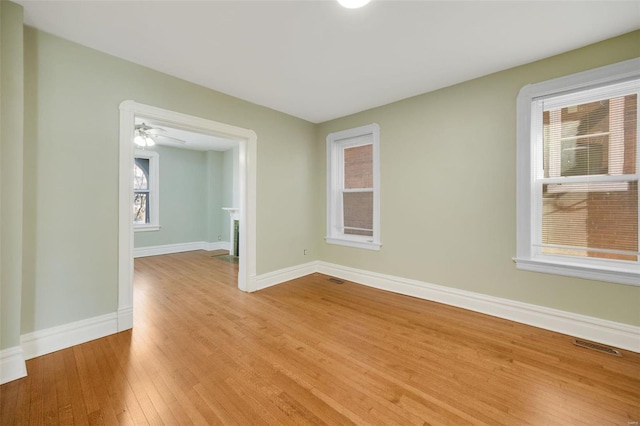 empty room featuring visible vents, light wood-type flooring, and baseboards