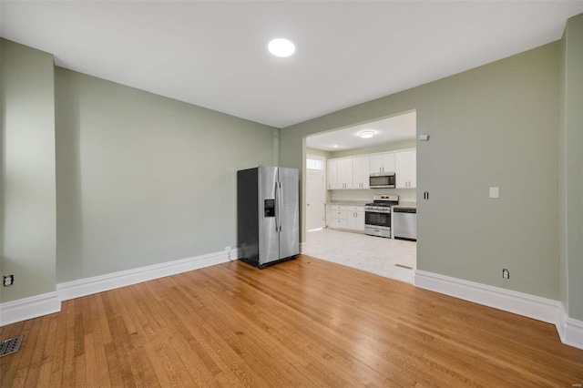 unfurnished living room featuring baseboards and light wood finished floors