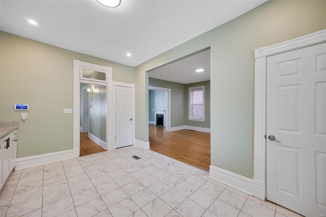 interior space featuring a fireplace, marble finish floor, and baseboards