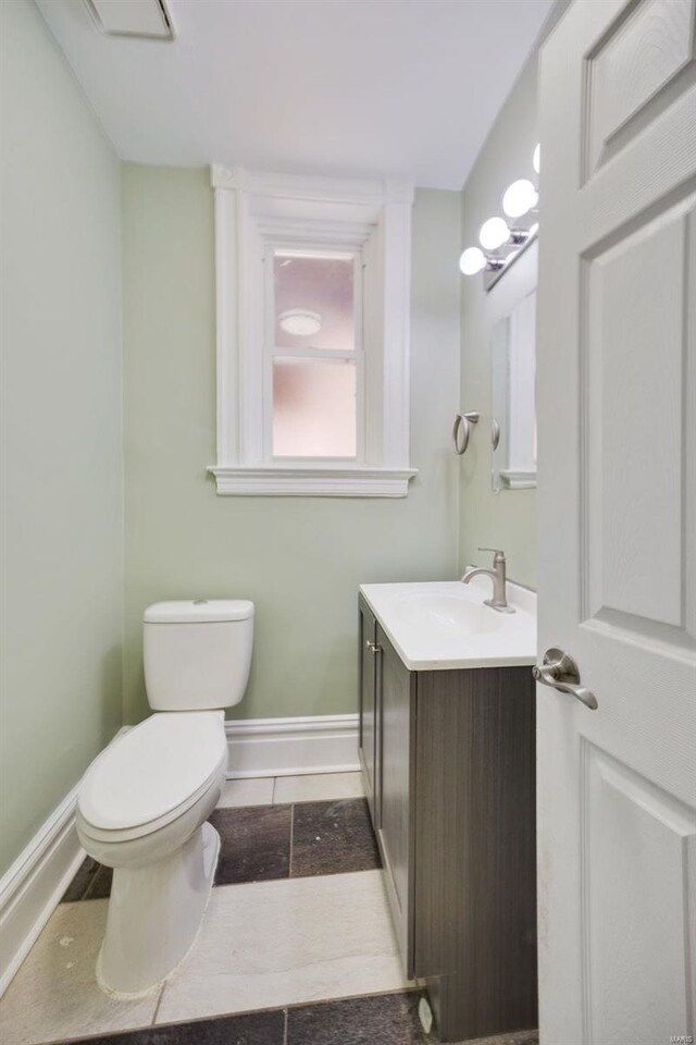 bathroom with toilet, vanity, and baseboards