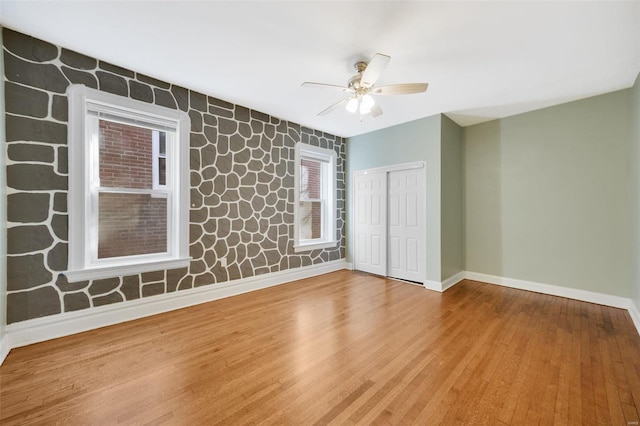 spare room with baseboards, wood finished floors, and a ceiling fan