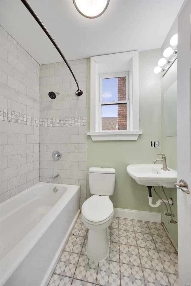 bathroom featuring baseboards, a sink, tile patterned floors, toilet, and shower / bathtub combination