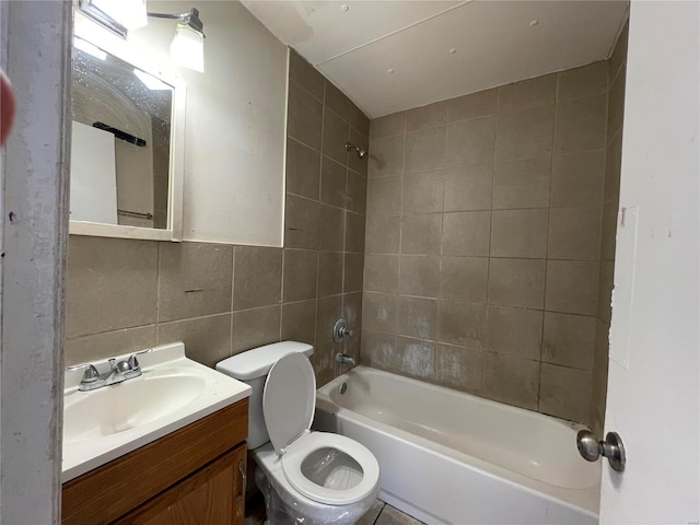 full bathroom with tiled shower / bath, tile walls, backsplash, vanity, and toilet