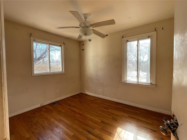 empty room featuring ceiling fan, a wealth of natural light, and dark hardwood / wood-style flooring