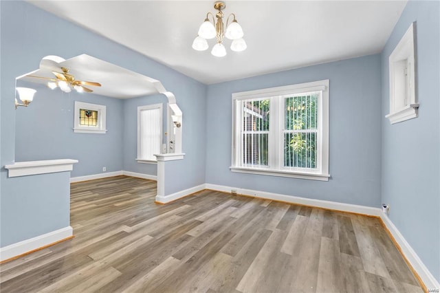 unfurnished room featuring ceiling fan with notable chandelier and light hardwood / wood-style floors